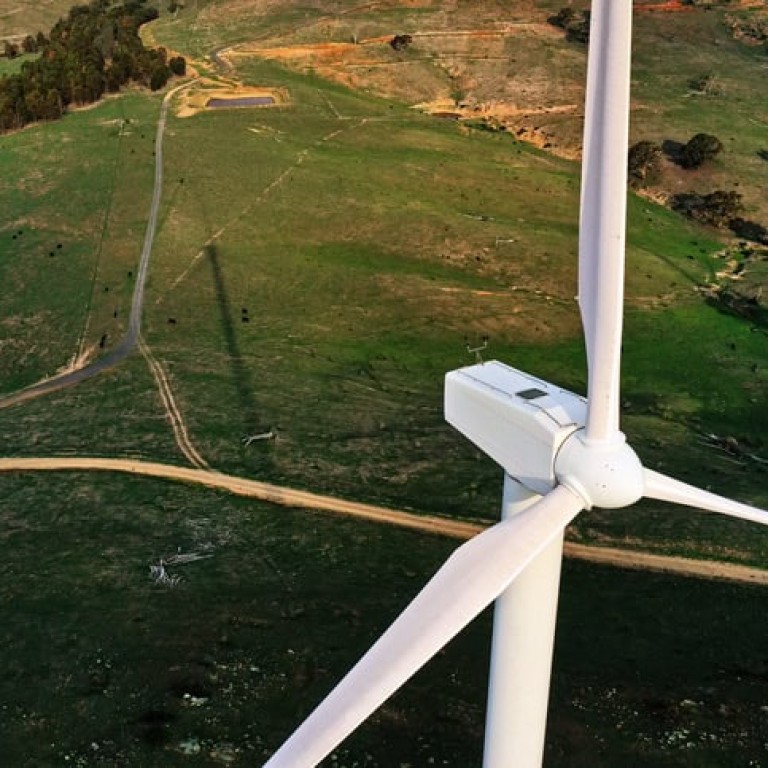 Wind turbine, wind farm in green field with dirt road, renewable energy in Australia